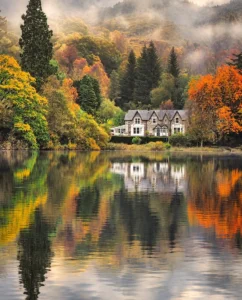 Colores de otoño y una casa reflejada en un lago de Escocia