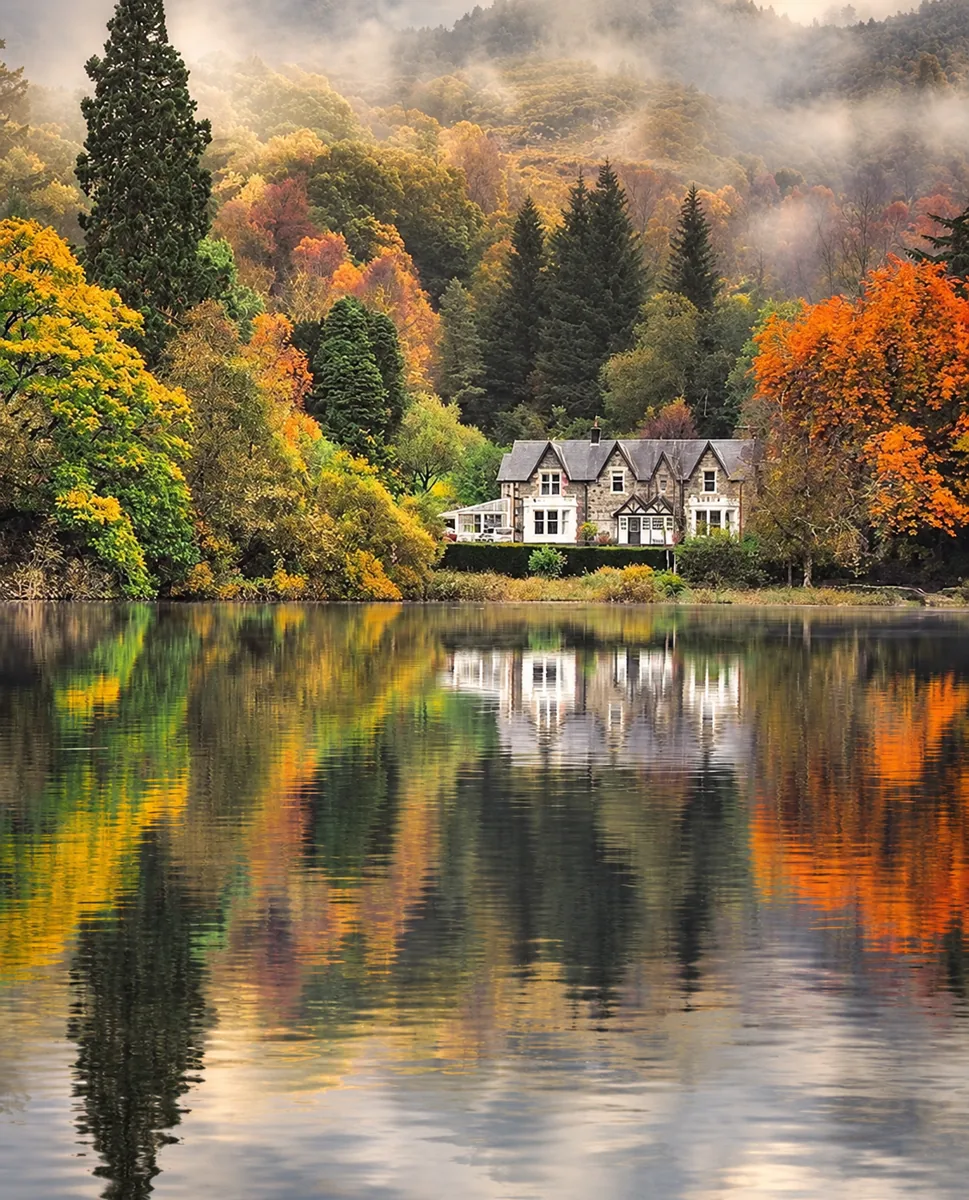 Colores de otoño y una casa reflejada en un lago de Escocia